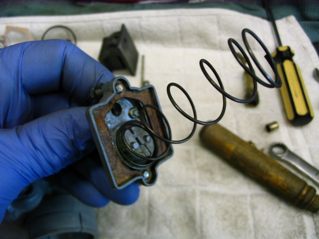 Insert the bent end into the carburetor top. This holds the spring in place.